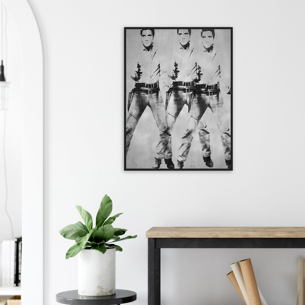 Andy Warhol framed print depicting a repeated standing figure in Western costume amplifies the rhythm of the pose, blending the visual language of a publicity still with a repeated screen image; Warhol’s multiple-Elvis imagery grew from publicity photographs of Elvis Presley in his Western-film